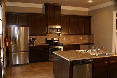 Full kitchen with dark cabinetry, granite counters, and stainless appliances